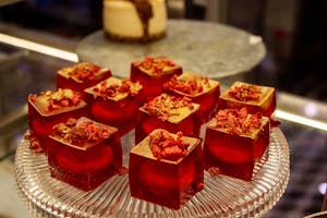 Elegant red jelly desserts topped with gold flakes and berries on a glass platter, perfect for gourmet presentations.