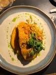 Elegant salmon fillet with vegetables and sauce on a white plate.