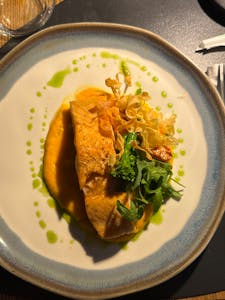 Elegant salmon fillet with vegetables and sauce on a white plate.