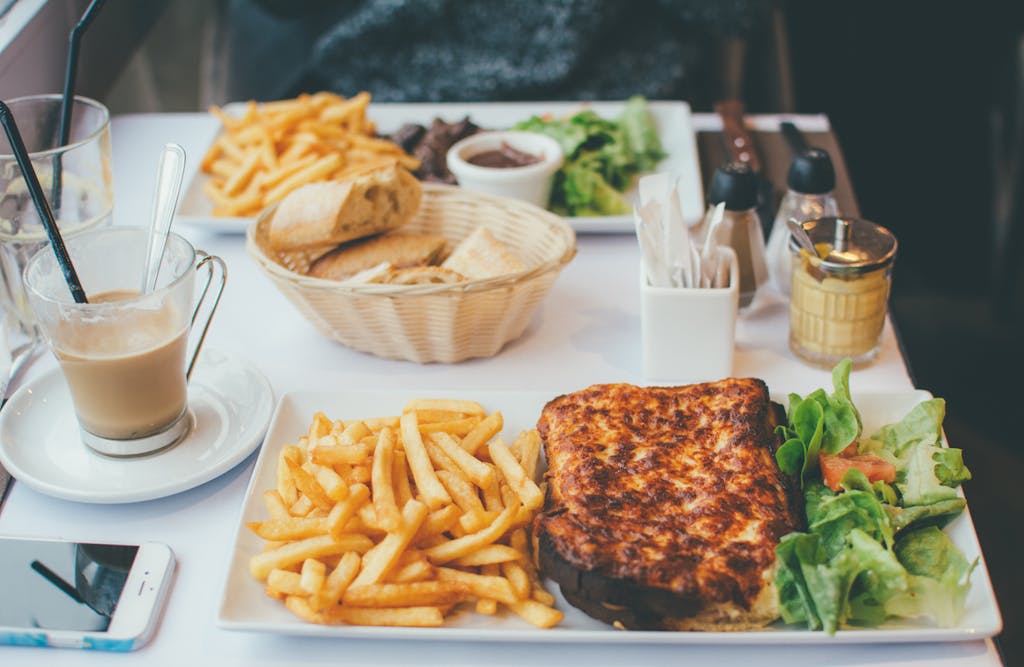 Enjoy a delightful meal with croque monsieur, fries, and salad at a Parisian bistro.