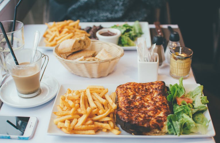 Enjoy a delightful meal with croque monsieur, fries, and salad at a Parisian bistro.