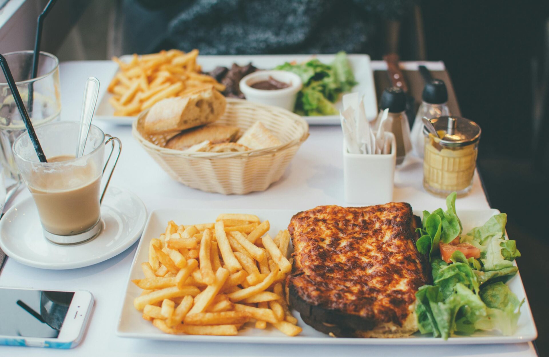 Enjoy a delightful meal with croque monsieur, fries, and salad at a Parisian bistro.
