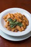 Enjoy a plate of Italian tortiglioni pasta with a rich tomato and meat sauce, garnished with fresh basil.