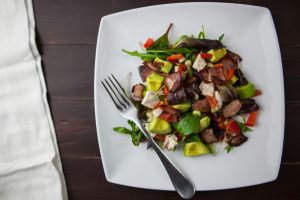Avocado chicken bacon salad on a white plate.