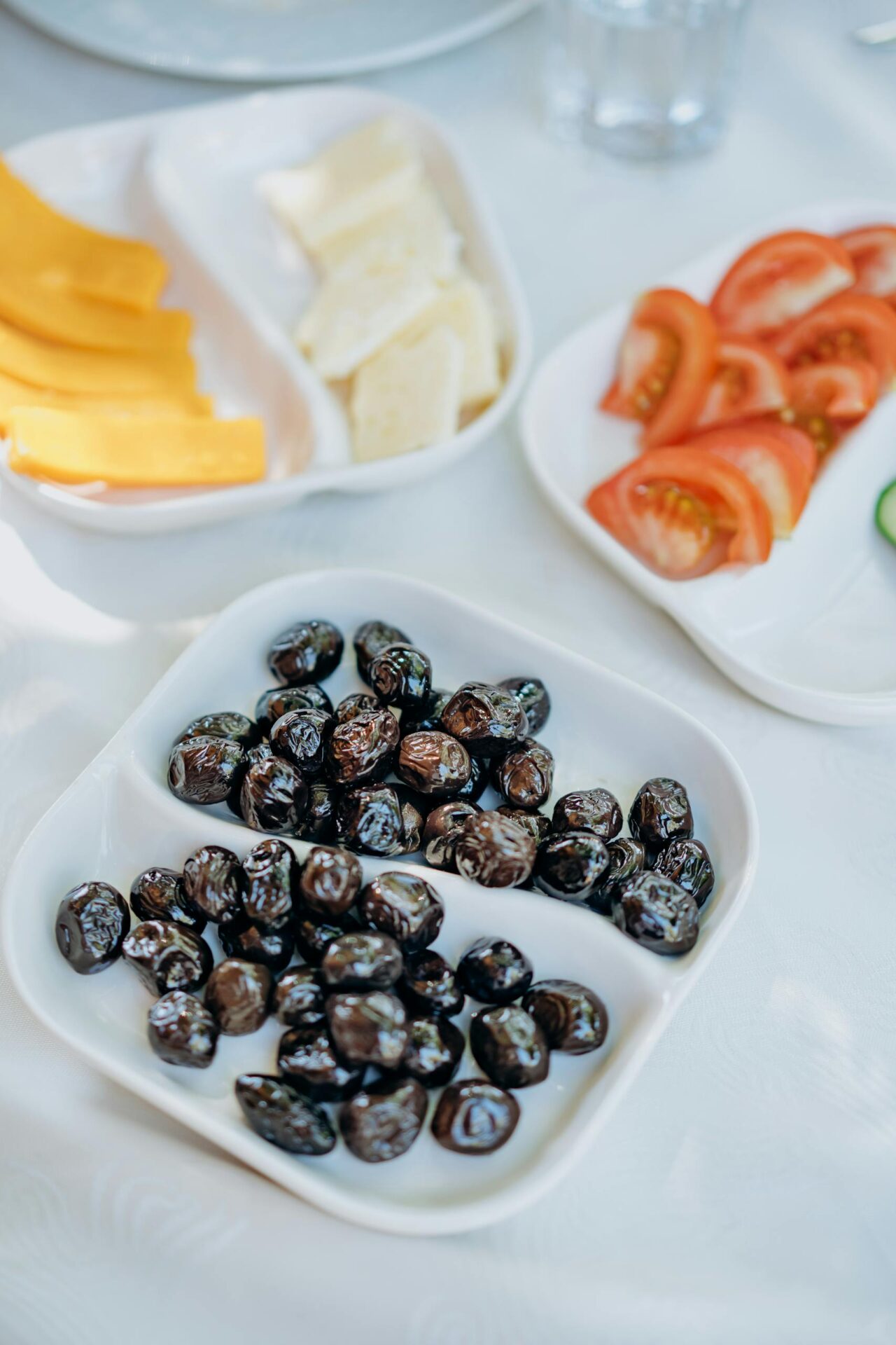 Fresh black olives with cheese, tomatoes, and mango slices, perfect for a healthy breakfast.