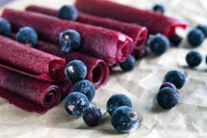 Rolled fruit leather with black currants on craft paper.