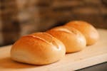 Golden brown bread rolls on a wooden board, perfect for breakfast or a tasty snack.