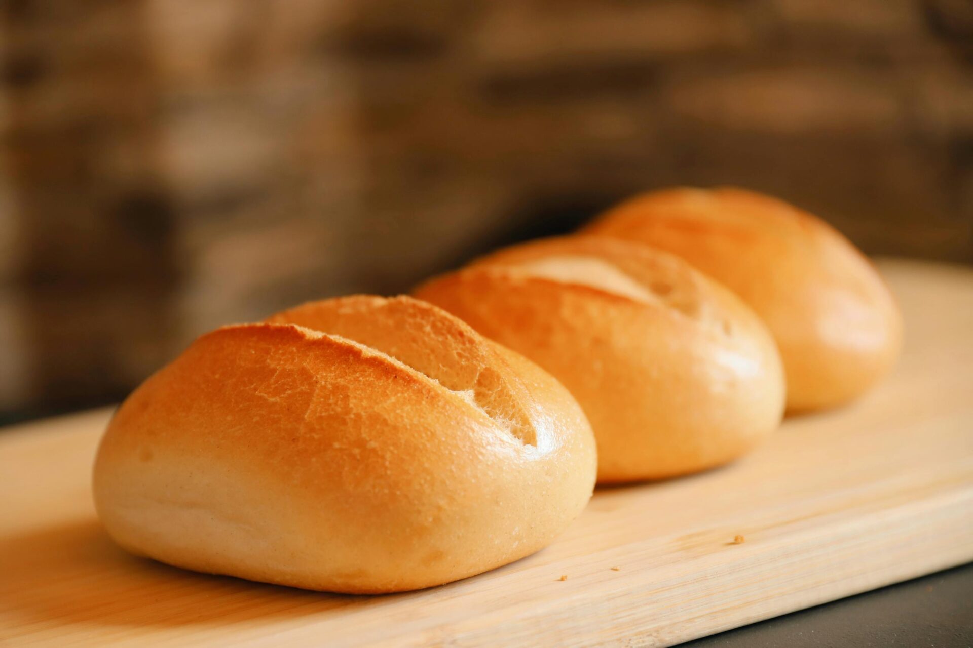 Golden brown bread rolls on a wooden board, perfect for breakfast or a tasty snack.
