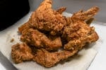 Golden brown fried chicken wings on a paper towel, showcasing a delicious, crispy texture.