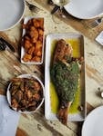 Gourmet herb-crusted whole fish with sides on rustic table, perfect for dining themes.