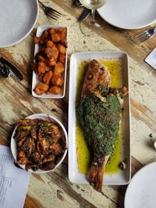 Gourmet herb-crusted whole fish with sides on rustic table, perfect for dining themes.