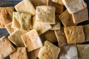 Assorted square baked crackers on a dark surface