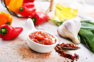 Small bowl of red hot sauce with chili peppers, garlic, and spices.
