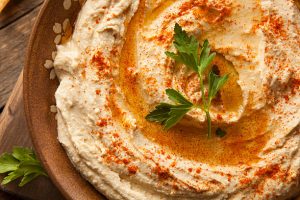 Creamy hummus topped with olive oil, paprika, and parsley in a serving bowl.