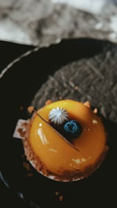 Indulge in this vibrant mango mousse cake topped with a fresh blueberry.