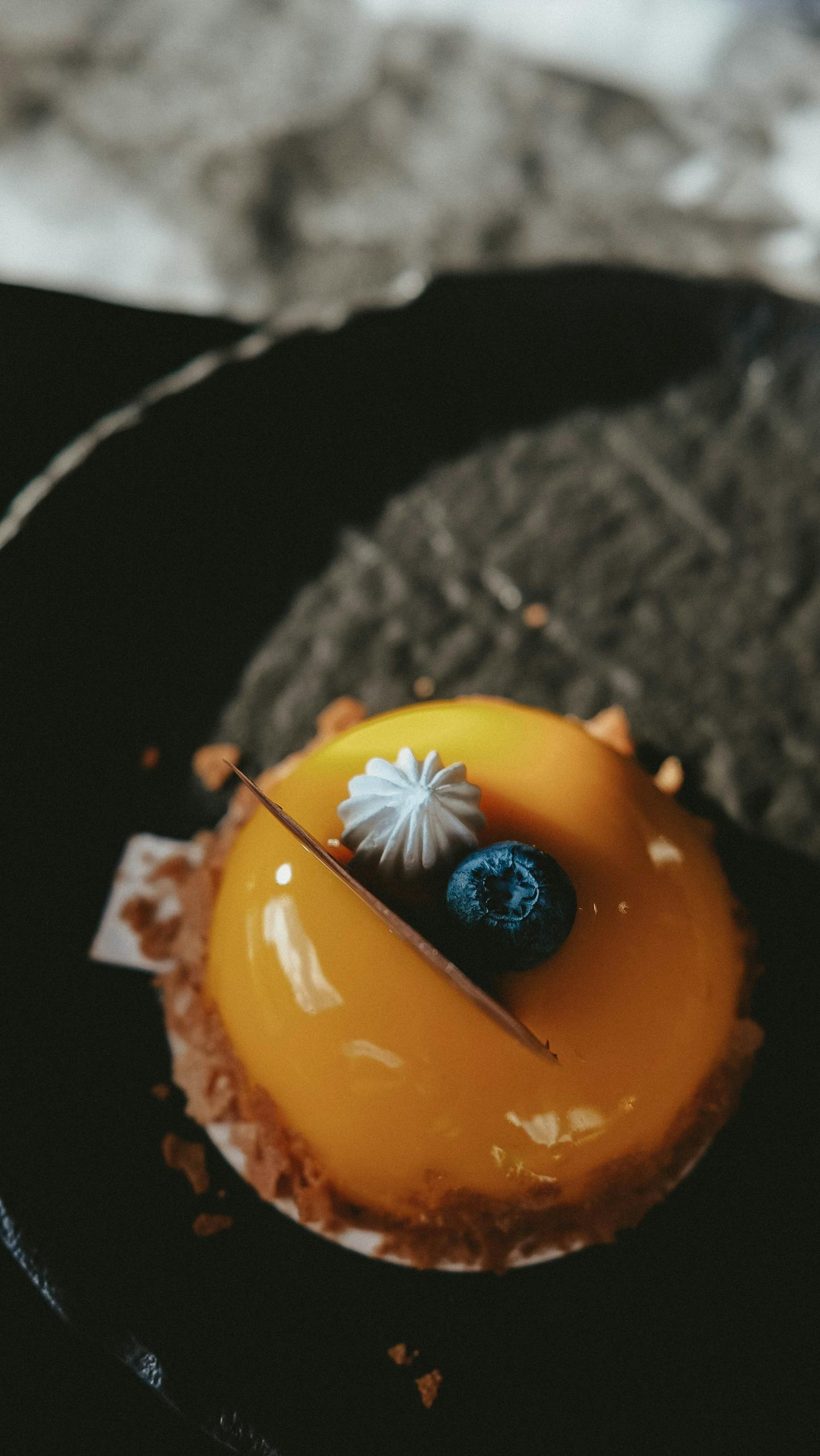 Indulge in this vibrant mango mousse cake topped with a fresh blueberry.