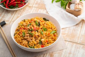 Bowl of stir-fried instant noodles with minced pork, holy basil, and red chilies