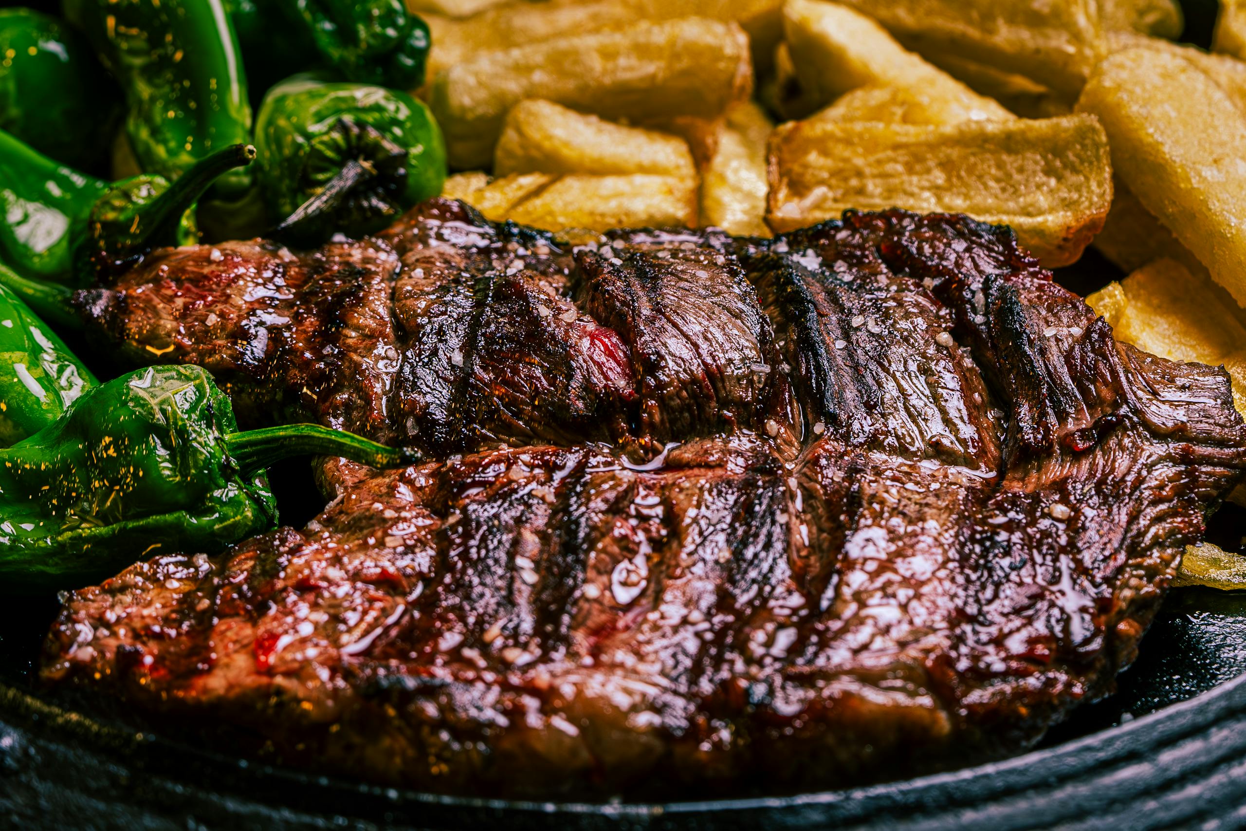 Juicy grilled steak with roasted green peppers and crispy potatoes for a savory meal.