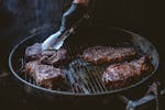 Juicy steaks being grilled over charcoal, perfect for a delicious BBQ meal.