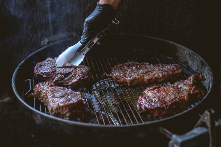 Juicy steaks being grilled over charcoal, perfect for a delicious BBQ meal.