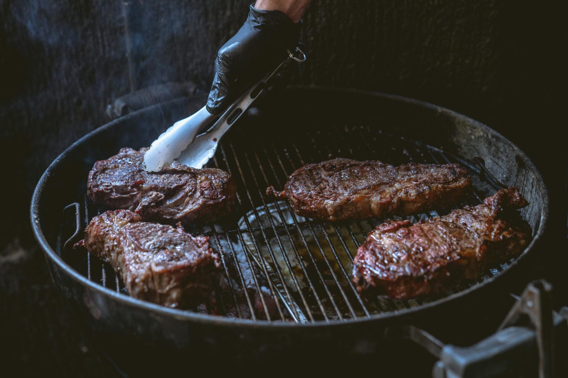 Juicy steaks being grilled over charcoal, perfect for a delicious BBQ meal.