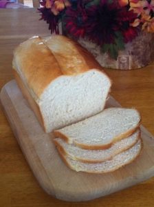 A loaf of white bread on a cutting board with several slices cut off.
