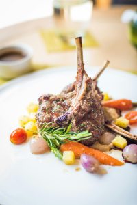 Plated lamb chops with roasted vegetables and herbs.