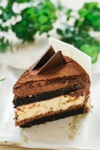 Slice of chocolate mousse cake topped with cocoa powder and chocolate garnish.