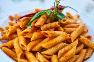 Penne pasta in tomato sauce topped with basil and a chili pepper.