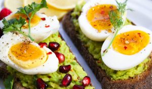 Avocado toast topped with soft-boiled eggs and pomegranate seeds