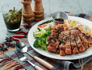 Grilled pork chops served with broccoli and fried rice on a plate