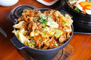 Stir-fried chicken with cabbage and carrots topped with sesame seeds and green onion.