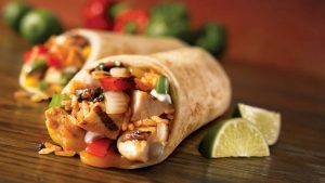 Chicken fajita wraps with grilled chicken, peppers, onions, and lime wedges.