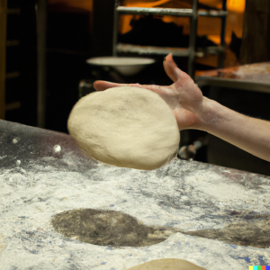 Hand tossing pizza dough over a floured surface