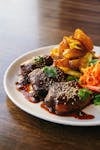 Savor a gourmet dish featuring glazed meat, roasted potatoes, and vibrant vegetables.