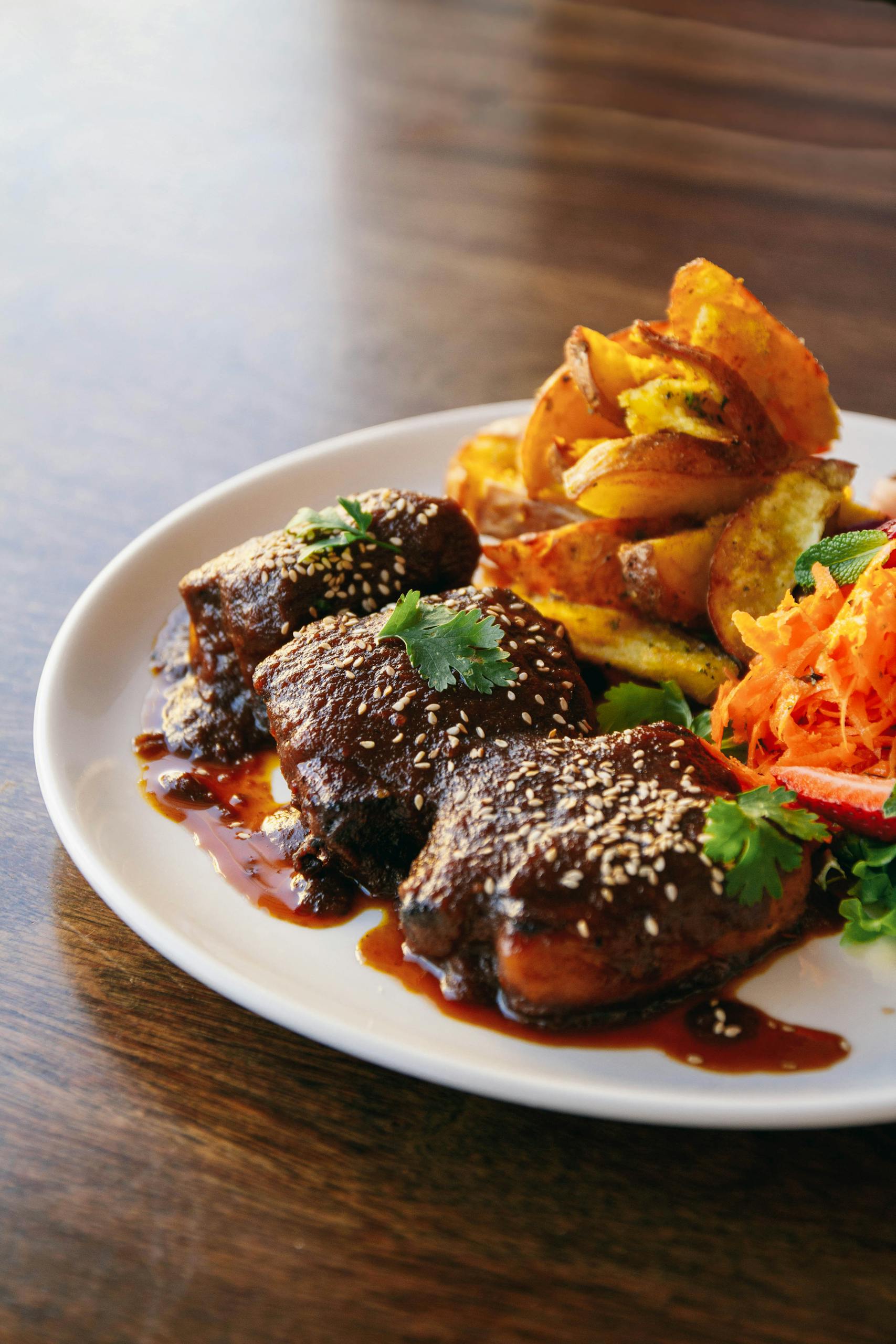 Savor a gourmet dish featuring glazed meat, roasted potatoes, and vibrant vegetables.