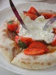 Savor the taste of fresh burrata cheese with juicy tomatoes on Italian flatbread.