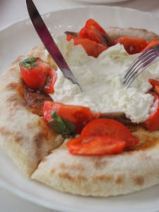 Savor the taste of fresh burrata cheese with juicy tomatoes on Italian flatbread.