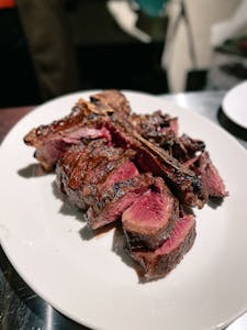 Sliced rare steak served on a white ceramic plate, capturing its juicy and delicious texture.