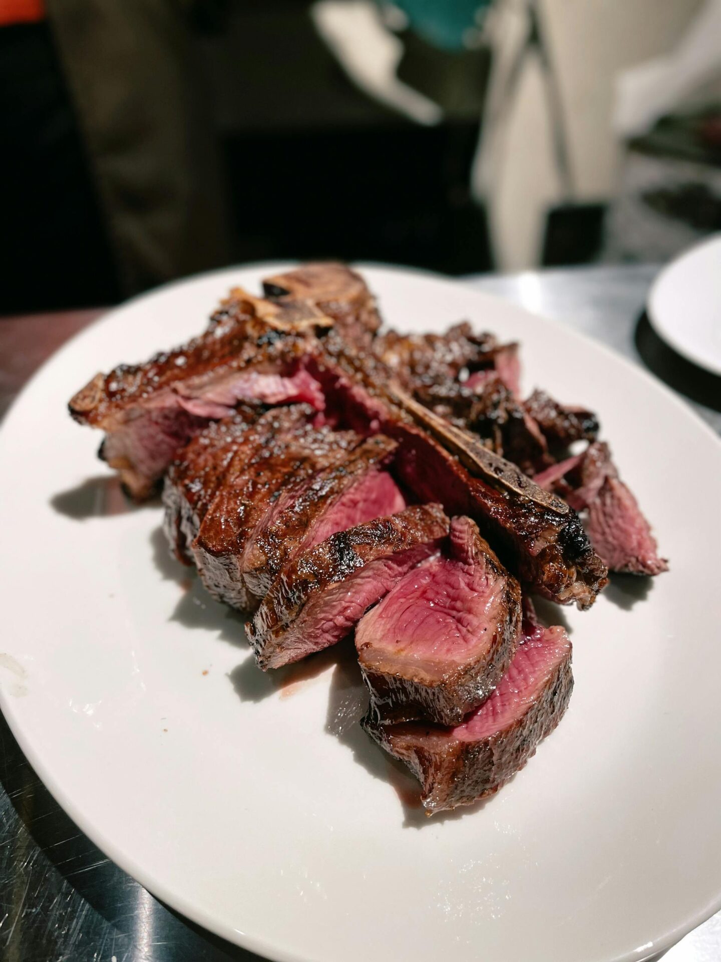 Sliced rare steak served on a white ceramic plate, capturing its juicy and delicious texture.