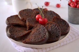 Slices of rich chocolate cake garnished with fresh cherries on a plate.