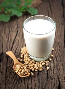 Glass of soy milk with soybeans on a wooden surface