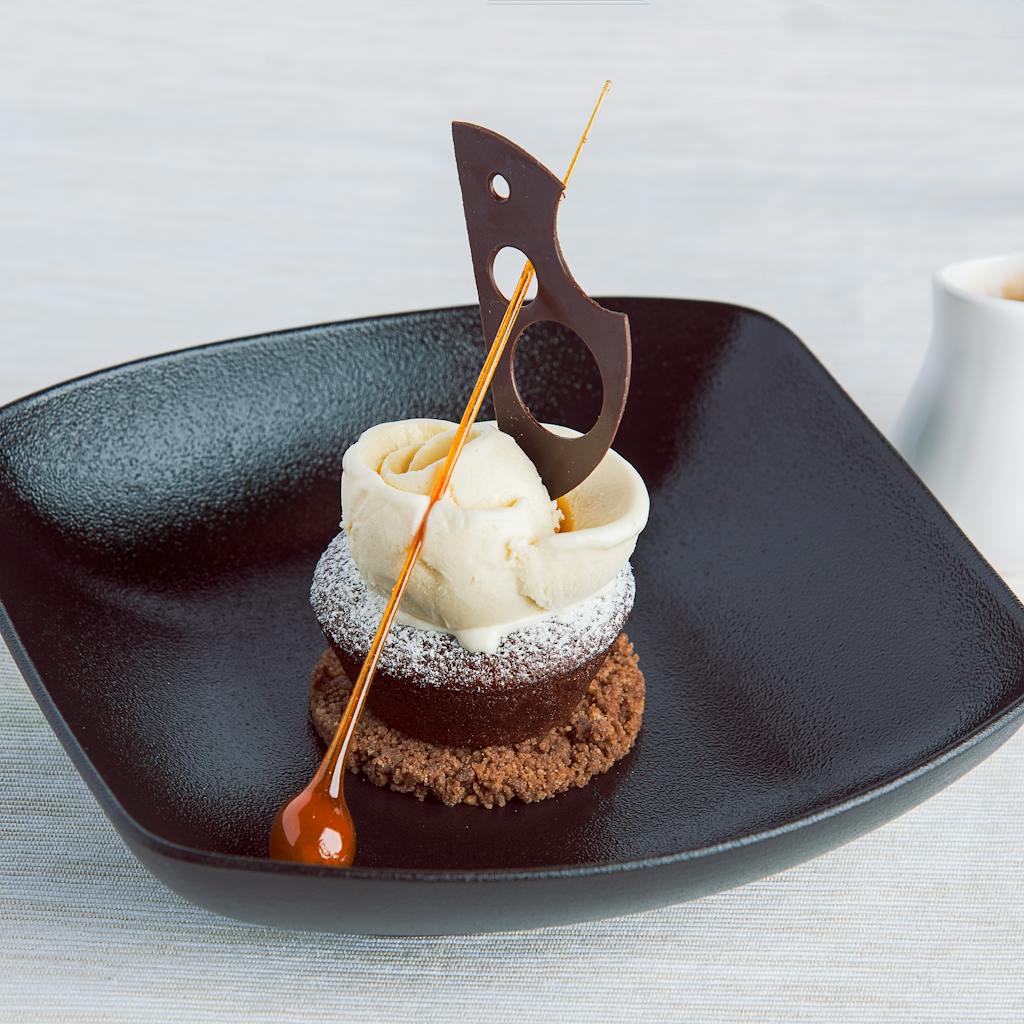 Stylish presentation of gourmet dessert with chocolate garnish and caramel accent.
