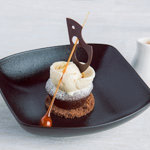 Stylish presentation of gourmet dessert with chocolate garnish and caramel accent.