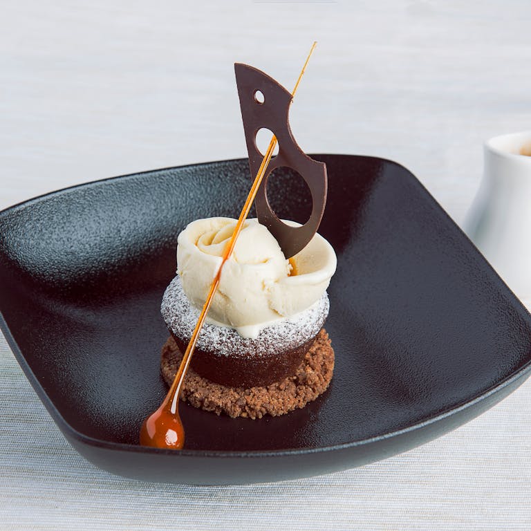 Stylish presentation of gourmet dessert with chocolate garnish and caramel accent.