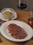 Succulent ribeye steak served with mashed potatoes and a glass of red wine.