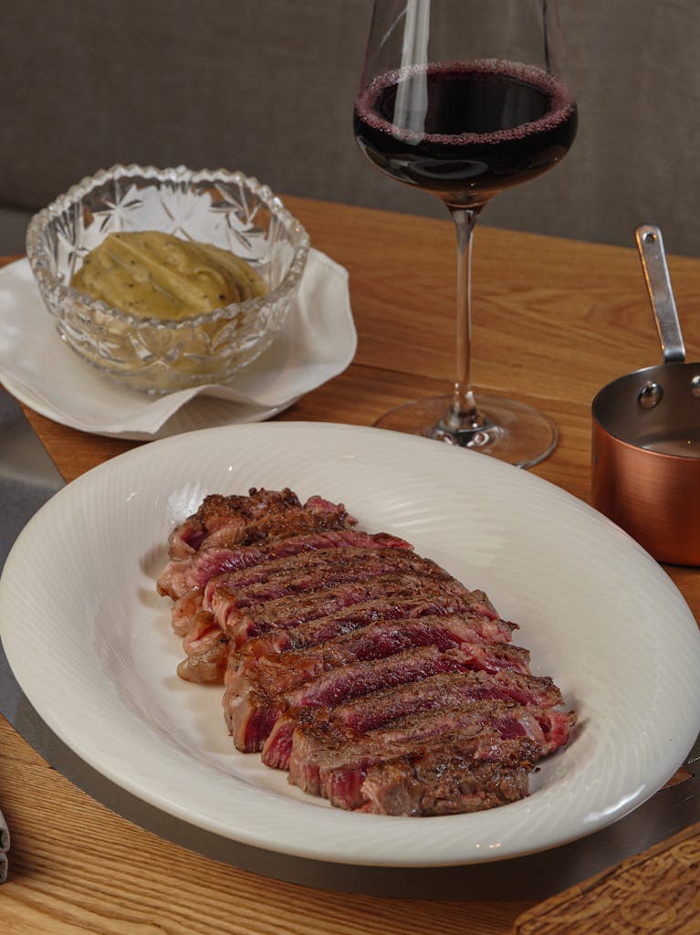 Succulent ribeye steak served with mashed potatoes and a glass of red wine.