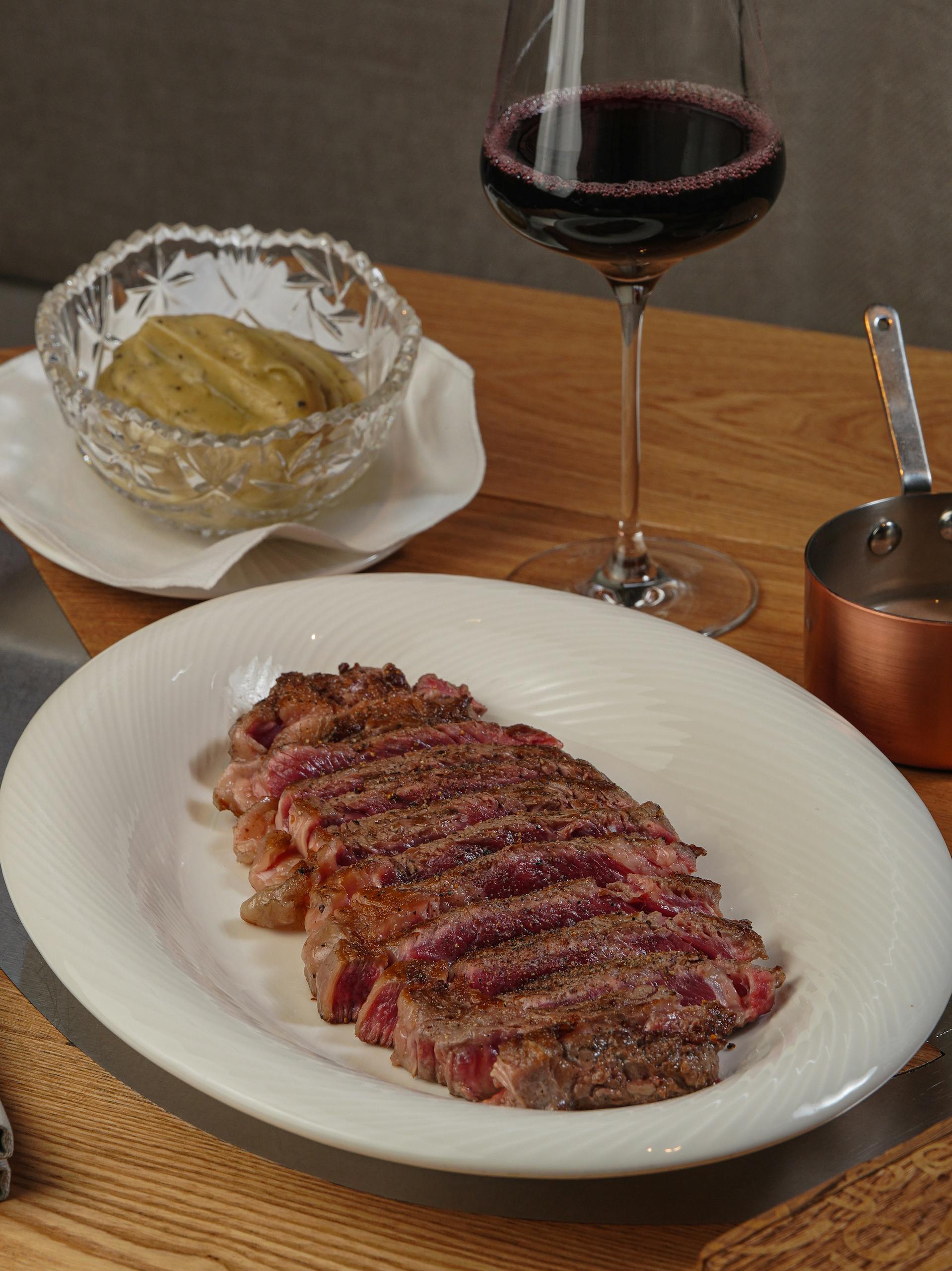 Succulent ribeye steak served with mashed potatoes and a glass of red wine.