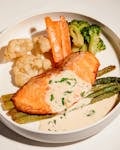Tasty salmon fillet with creamy sauce, paired with fresh vegetables.