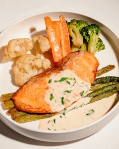Tasty salmon fillet with creamy sauce, paired with fresh vegetables.